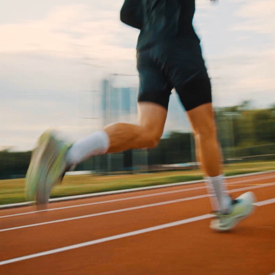 Athlete running on track wearing KINEX compression socks