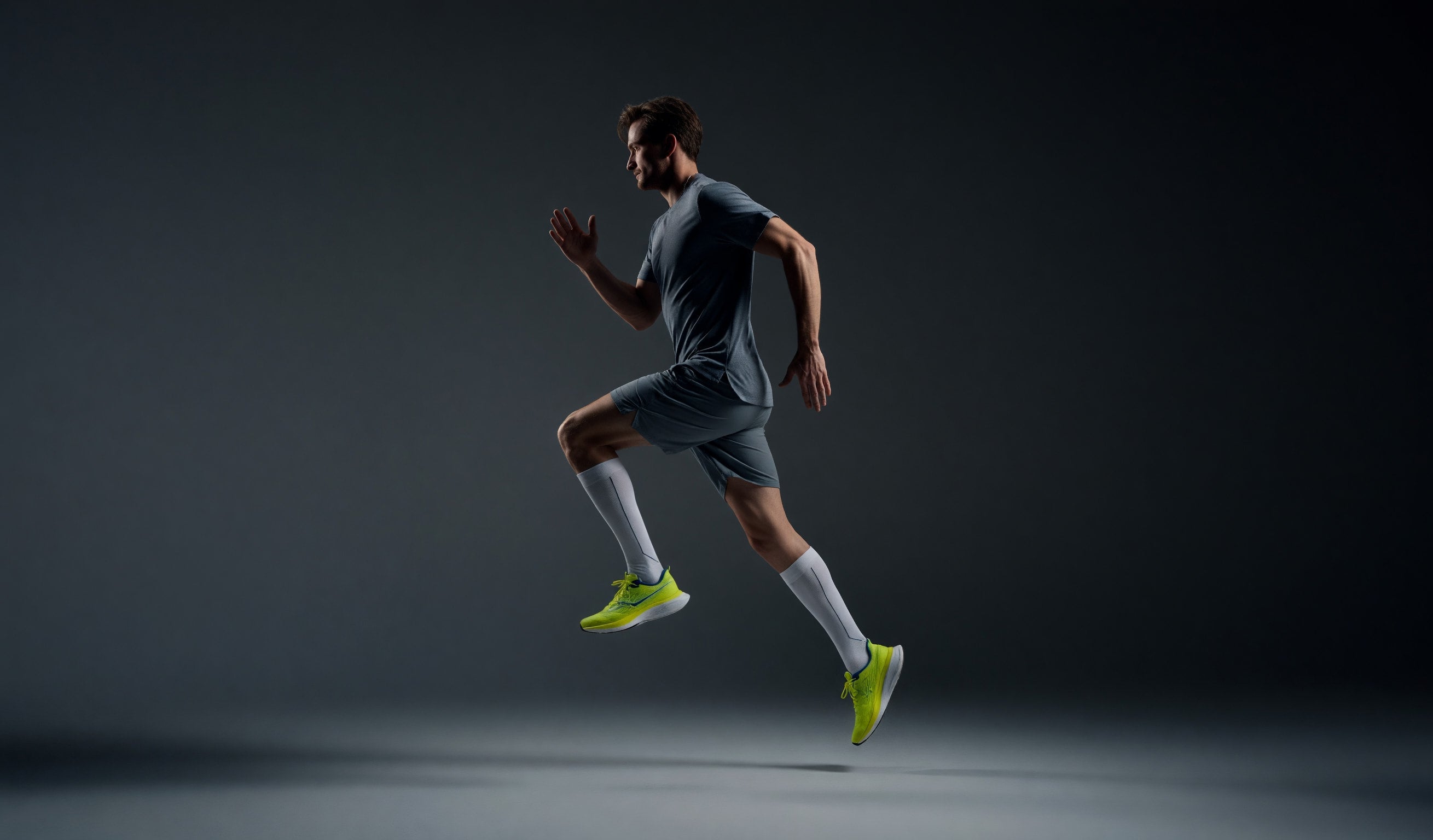 Running athlete wearing white kneehigh compression socks