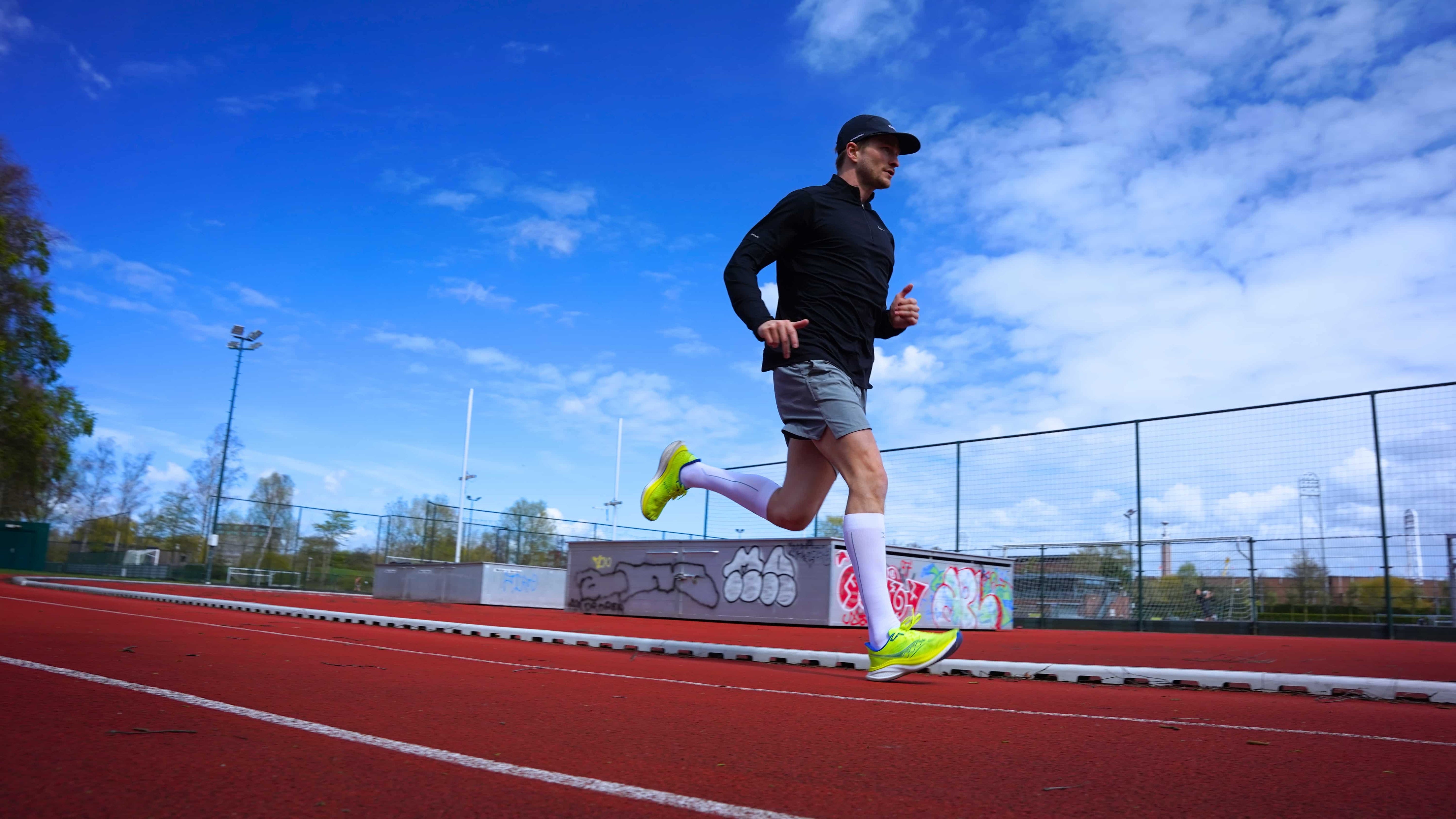 Running athlete wearing white knee-high compression socks